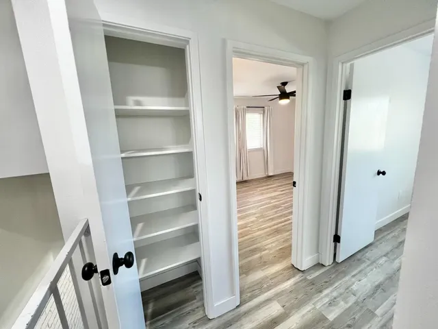 a view of a hallway with wooden floor and closet
