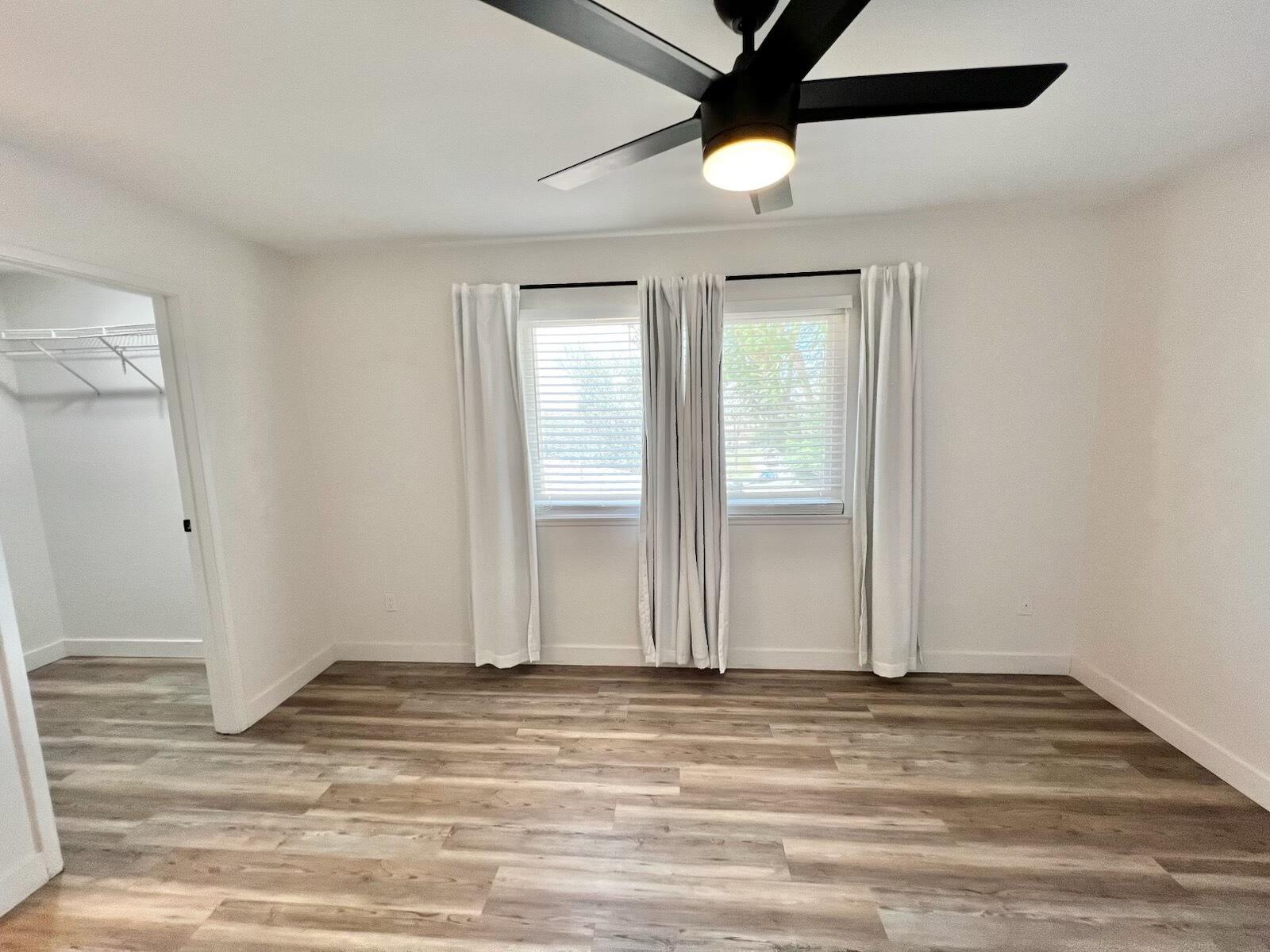 72671 Eagle Road, Unit 3 Palm Desert, CA 92260 - Photo 22 of 25 an empty room with wooden floor chandelier fan and windows