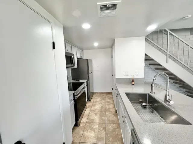 a kitchen with a sink a counter top space stainless steel appliances and cabinets