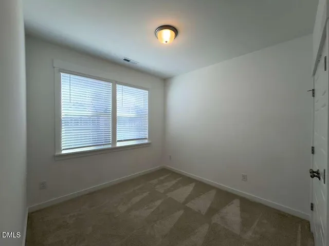 a view of a hallway with wooden floor and a bathroom