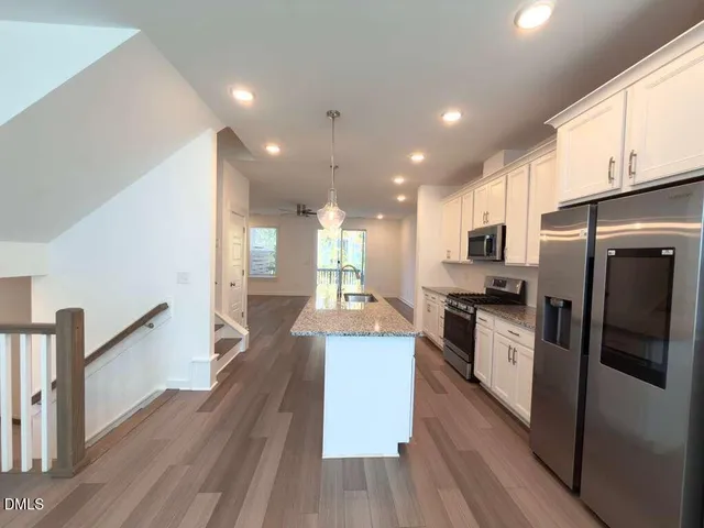 a view of a kitchen with a sink refrigerator and wooden floor