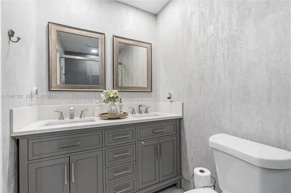 a bathroom with a toilet a sink a vanity and mirror