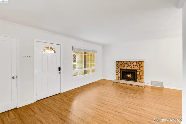 a view of an empty room with wooden floor fireplace and a window