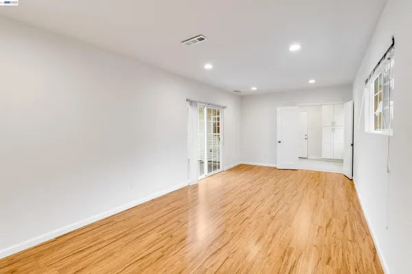a view of empty room with wooden floor and fan