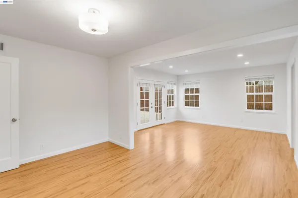 a view of an empty room with wooden floor and windows