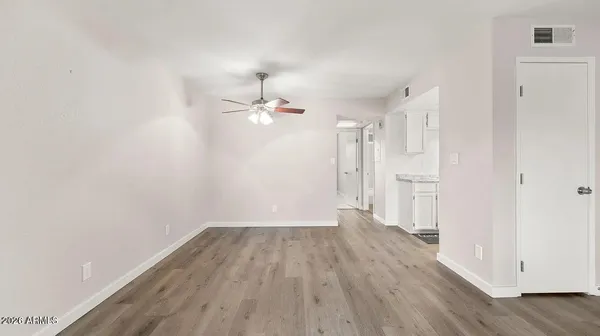 an empty room with wooden floor cabinet and windows