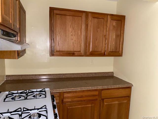 199 Hoover Road, Unit 2F Yonkers, NY 10710 - Photo 12 of 16 Kitchen with brown cabinets and white range with gas cooktop