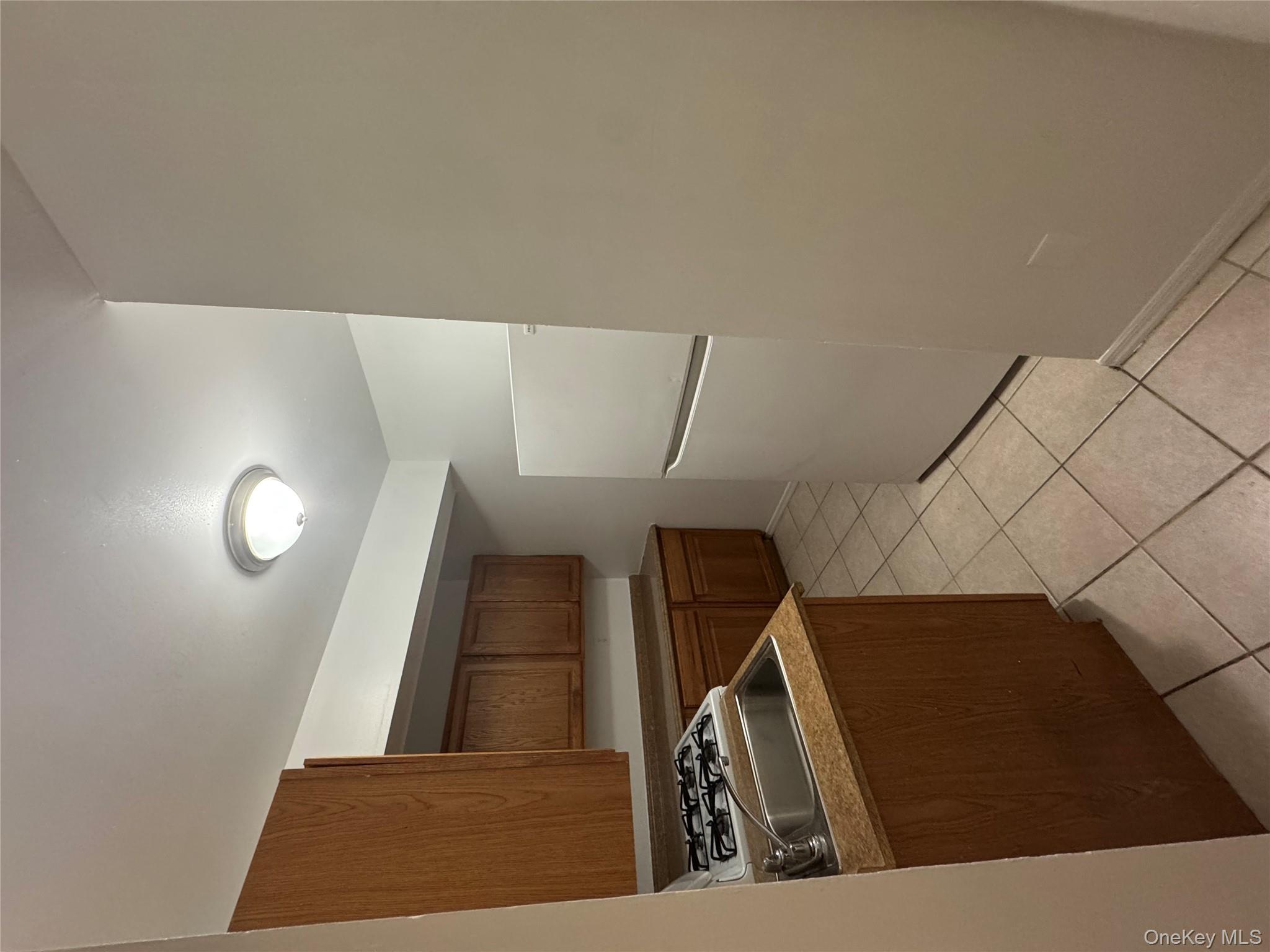 199 Hoover Road, Unit 2F Yonkers, NY 10710 - Photo 13 of 16 Kitchen featuring white refrigerator, light tile patterned flooring, and brown cabinets