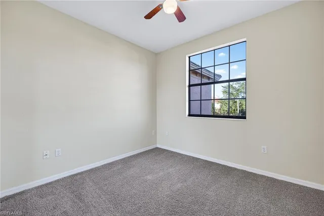 an empty room with a window and a ceiling fan