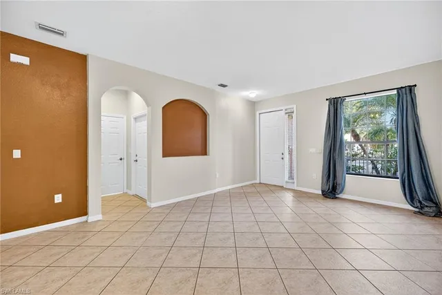 a view of an empty room with window and mirror