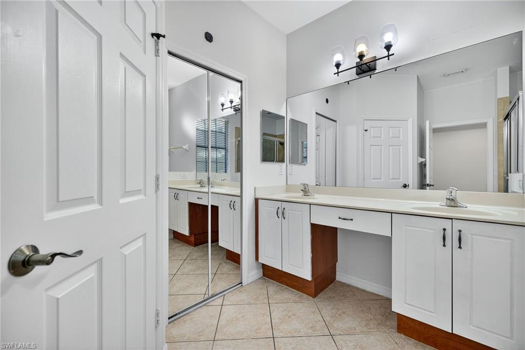 7666 Bristol Circle Naples, FL 34120 - Photo 9 of 19 a spacious bathroom with a double vanity sink a mirror and a shower