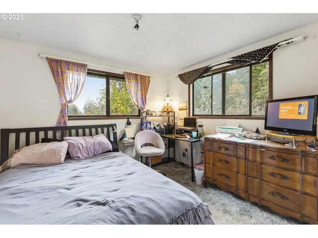 a bedroom with a bed and large windows