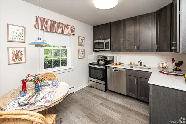 a kitchen with stainless steel appliances granite countertop a stove top oven a sink dishwasher and a microwave oven on the wooden floor