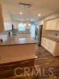 a view of a kitchen with kitchen island a sink wooden floor and a counter top space