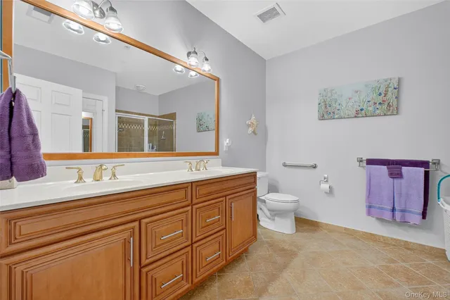 a spacious bathroom with a granite countertop double vanity sink a mirror and a toilet
