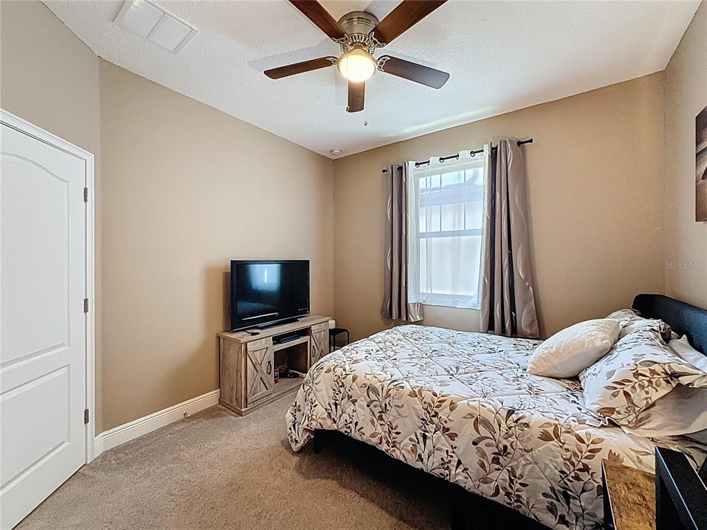 3193 Crispin Circle Harmony, FL 34773 - Photo 22 of 64 a bedroom with a bed and a flat tv screen on dresser