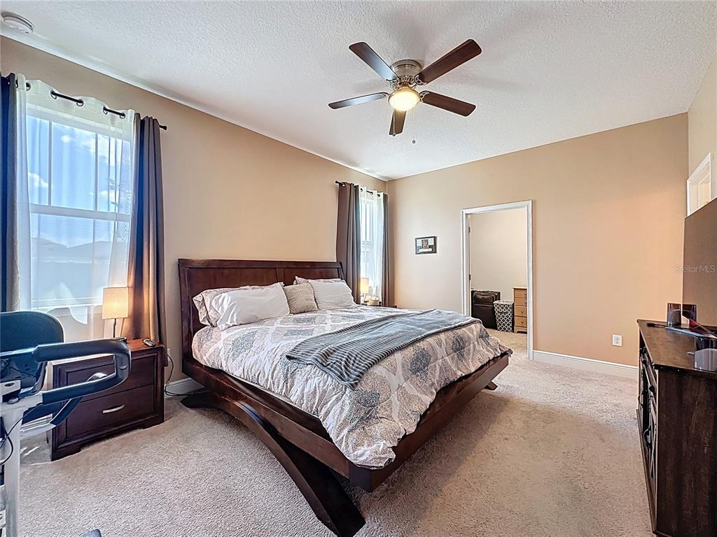 3193 Crispin Circle Harmony, FL 34773 - Photo 25 of 64 a bedroom with a large bed and a chandelier