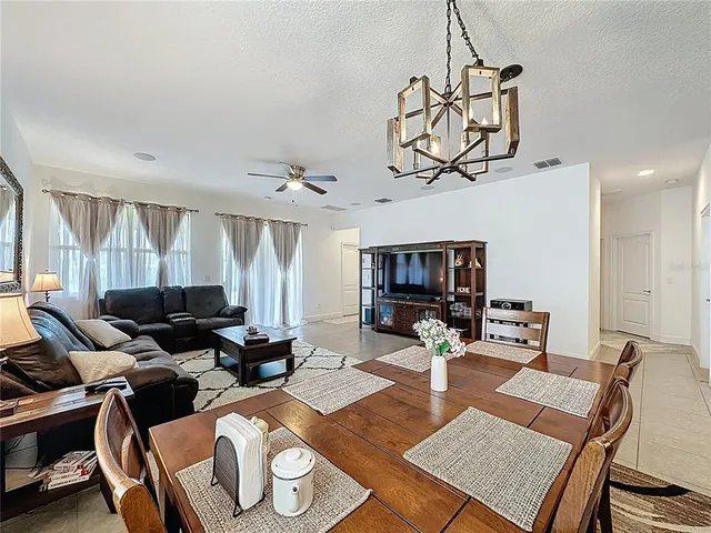 a living room with furniture a flat screen tv and a chandelier