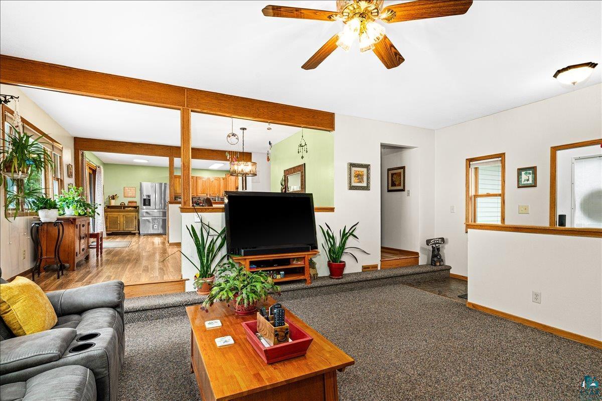 130 West Austin Street Duluth, MN 55803 - Photo 5 of 35 Open-concept living area featuring wood-finish structural beams and trim, carpeted flooring, and a ceiling fan with integrated lighting