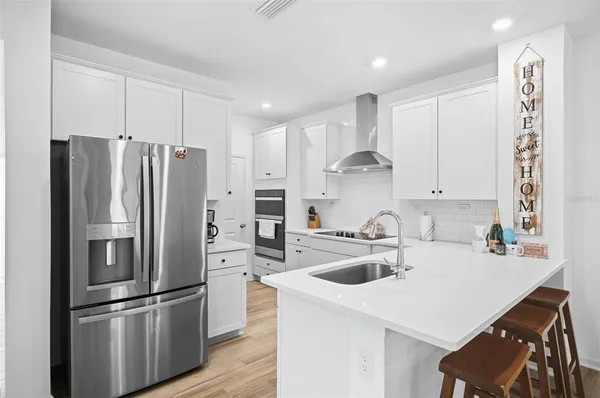 a kitchen that has a refrigerator a sink and white cabinets