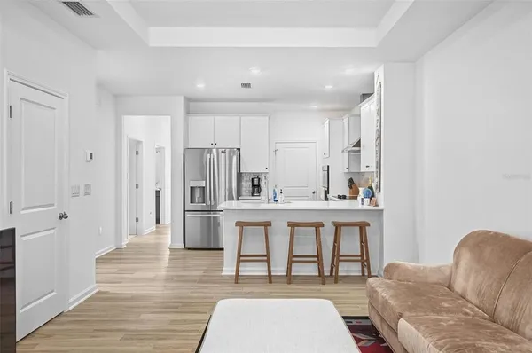 a living room with stainless steel appliances furniture a refrigerator and kitchen view