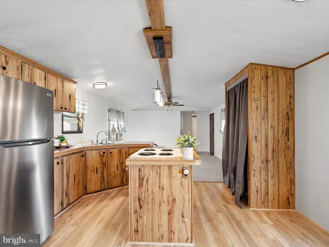 a kitchen with stainless steel appliances a refrigerator a stove a sink dishwasher and wooden cabinets with wooden floor