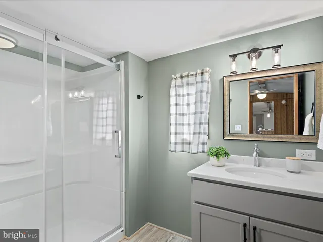 a bathroom with a granite countertop sink mirror and a shower