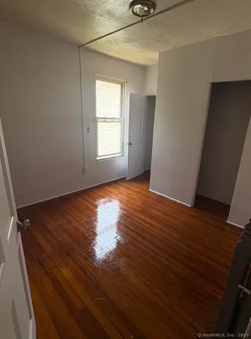 an empty room with wooden floor cabinet and windows