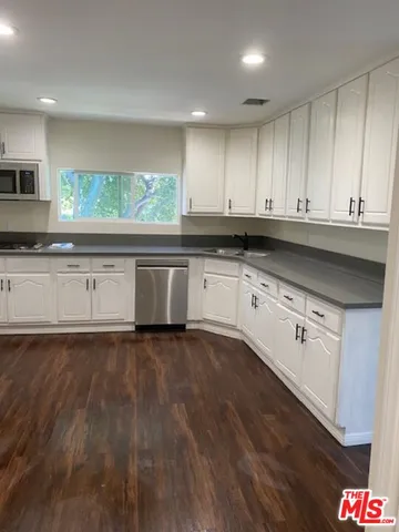 a kitchen with stainless steel appliances granite countertop a stove a sink and white cabinets