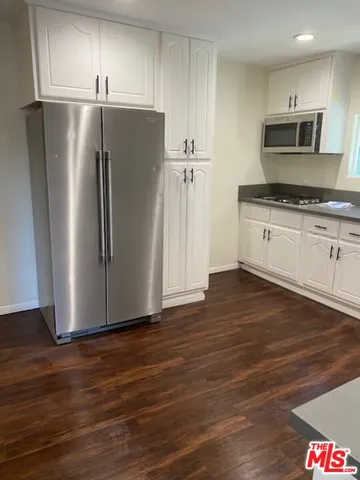 a kitchen with granite countertop a refrigerator and a stove top oven
