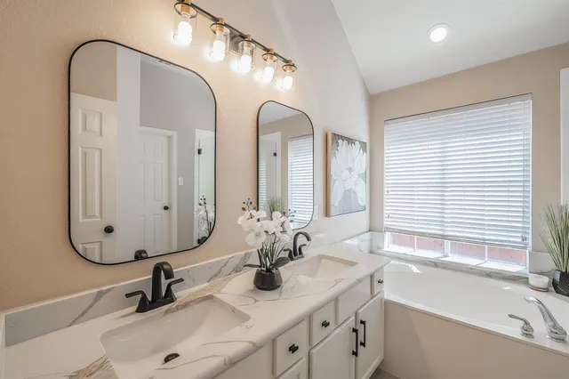 a bathroom with a tub a sink and a large mirror