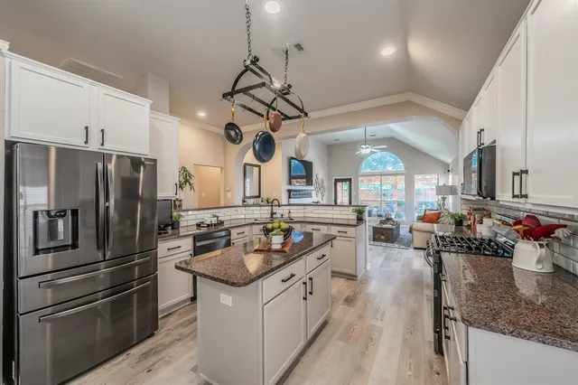 a kitchen with stainless steel appliances granite countertop a sink a stove and a refrigerator