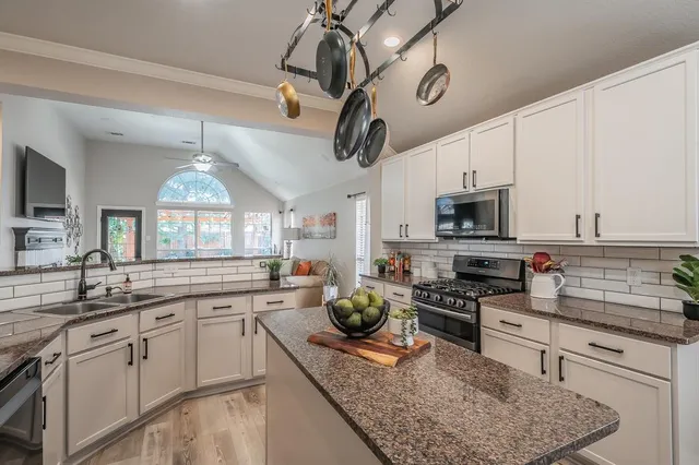 a kitchen with stainless steel appliances granite countertop a sink a stove and cabinets