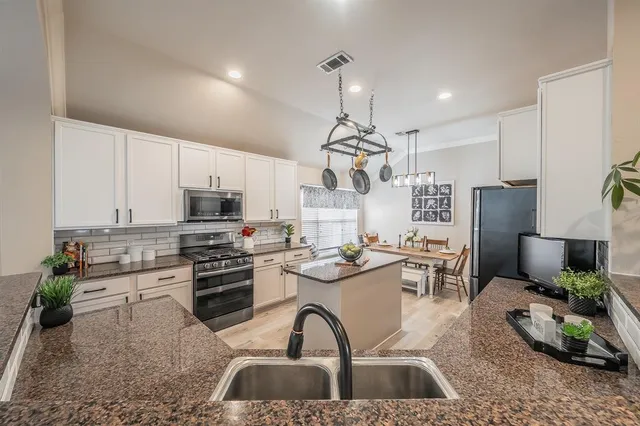 a kitchen with stainless steel appliances a stove a sink a refrigerator cabinets and living room view
