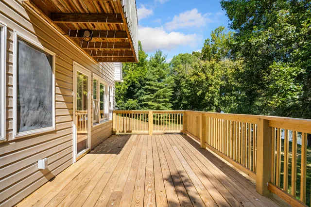 a view of a livingroom with a fireplace a ceiling fan and windows