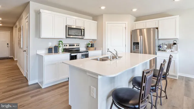 a kitchen with stainless steel appliances a table chairs microwave and refrigerator