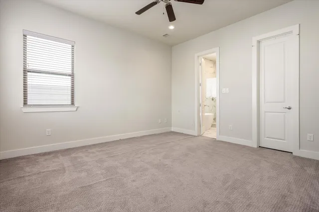 an empty room with chandelier fan and windows