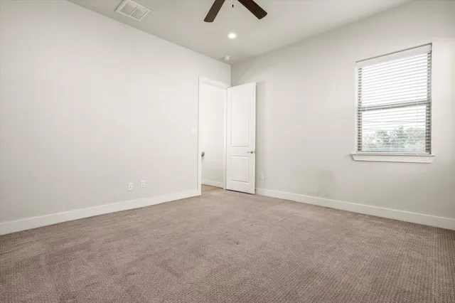 an empty room with chandelier fan and windows