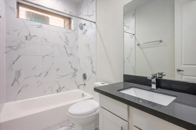 a bathroom with a granite countertop sink a toilet and a bathtub