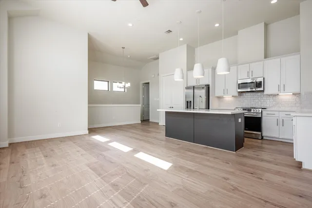 a large kitchen with stainless steel appliances granite countertop a large counter top a sink cabinets and a wooden floor