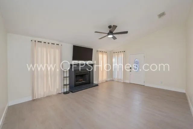 a view of a livingroom with a flat screen tv a ceiling fan and a window