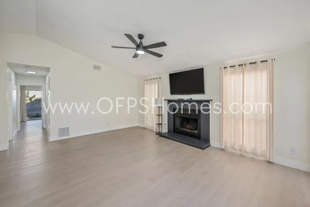 a view of a livingroom with a fireplace a ceiling fan and window