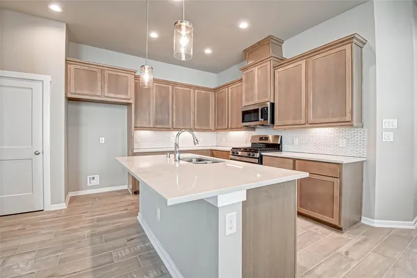 a kitchen with kitchen island a sink dishwasher a stove and a refrigerator with wooden floor