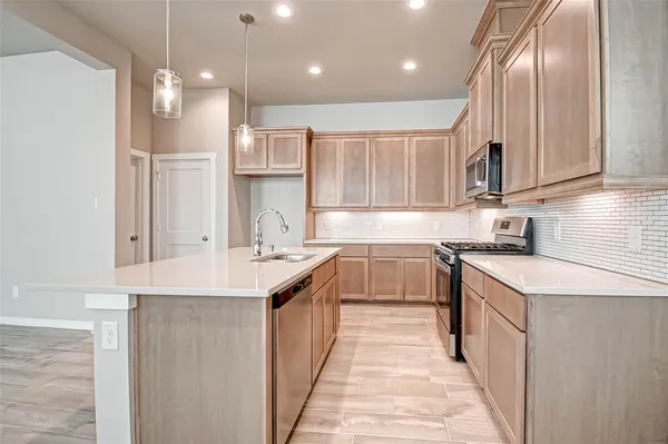 a kitchen with stainless steel appliances granite countertop a sink a stove and a refrigerator