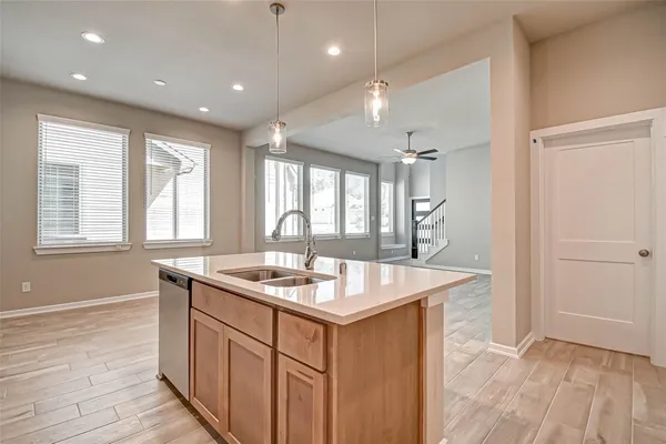 a hallway with kitchen island granite countertop a sink and wooden floor
