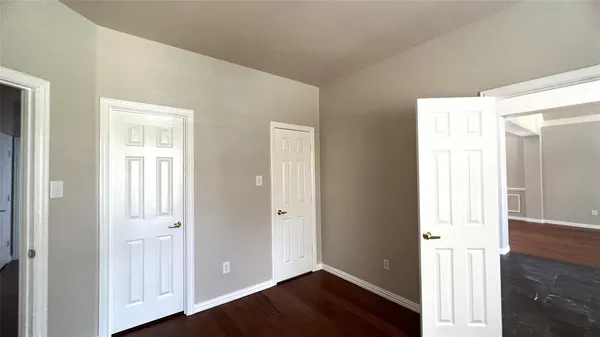 an empty room with wooden floor door and windows