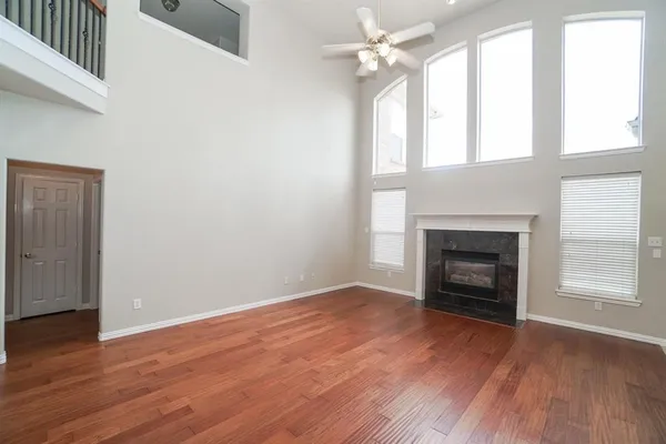an empty room with wooden floor fireplace and windows