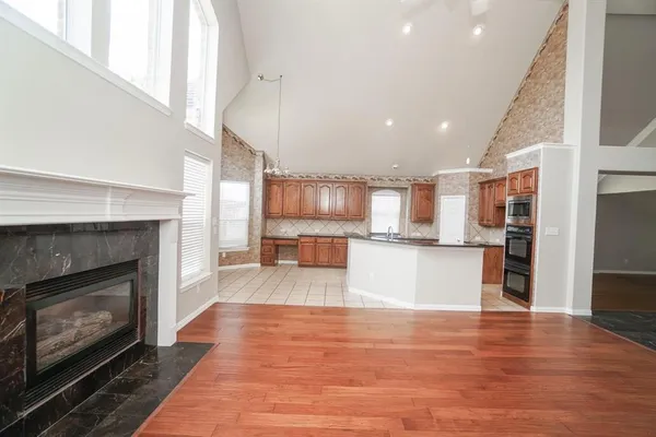 a view of kitchen with kitchen island wooden floor and stainless steel appliances
