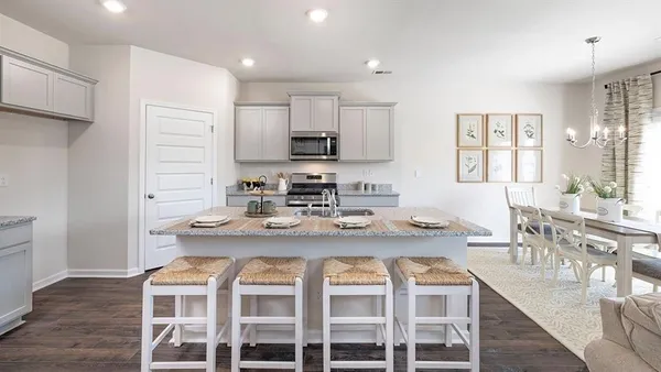 a kitchen with a dining table chairs and wooden floor