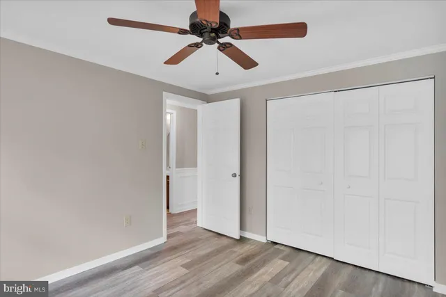 an empty room with wooden floor closet and fan
